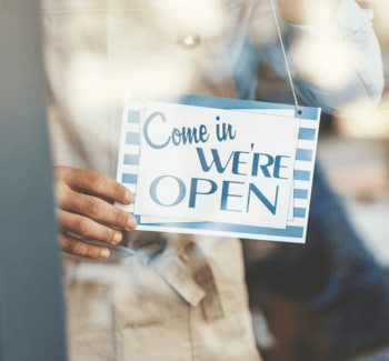Worker hanging "Come in, We're Open" sign