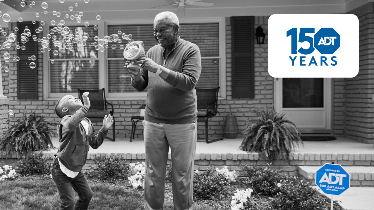 Grandpa playing with his kids in his yard with an ADT sign