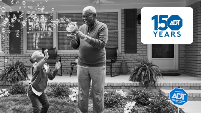 Grandpa playing with his kids in his yard with an ADT sign