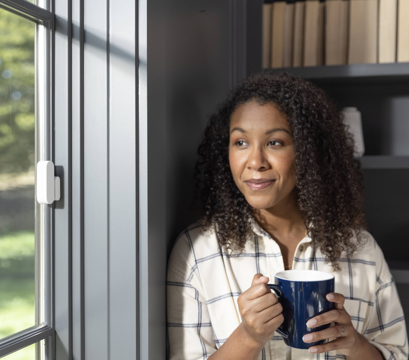 ADT customer standing next to her window that has a ADT Door/Window Sensor installed ADT customer standing next to her window that has a ADT Door/Window Sensor installed