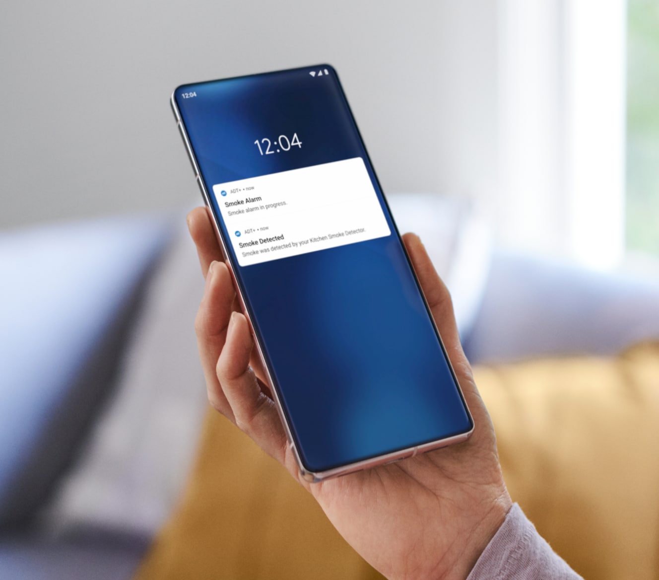 Hand holding a phone checking notifications from the ADT app Hand holding a phone checking notifications from the ADT app