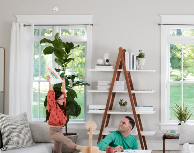 Family in the living room with an ADT Battery Smoke Detector on the wall Family in the living room with an ADT Battery Smoke Detector on the wall